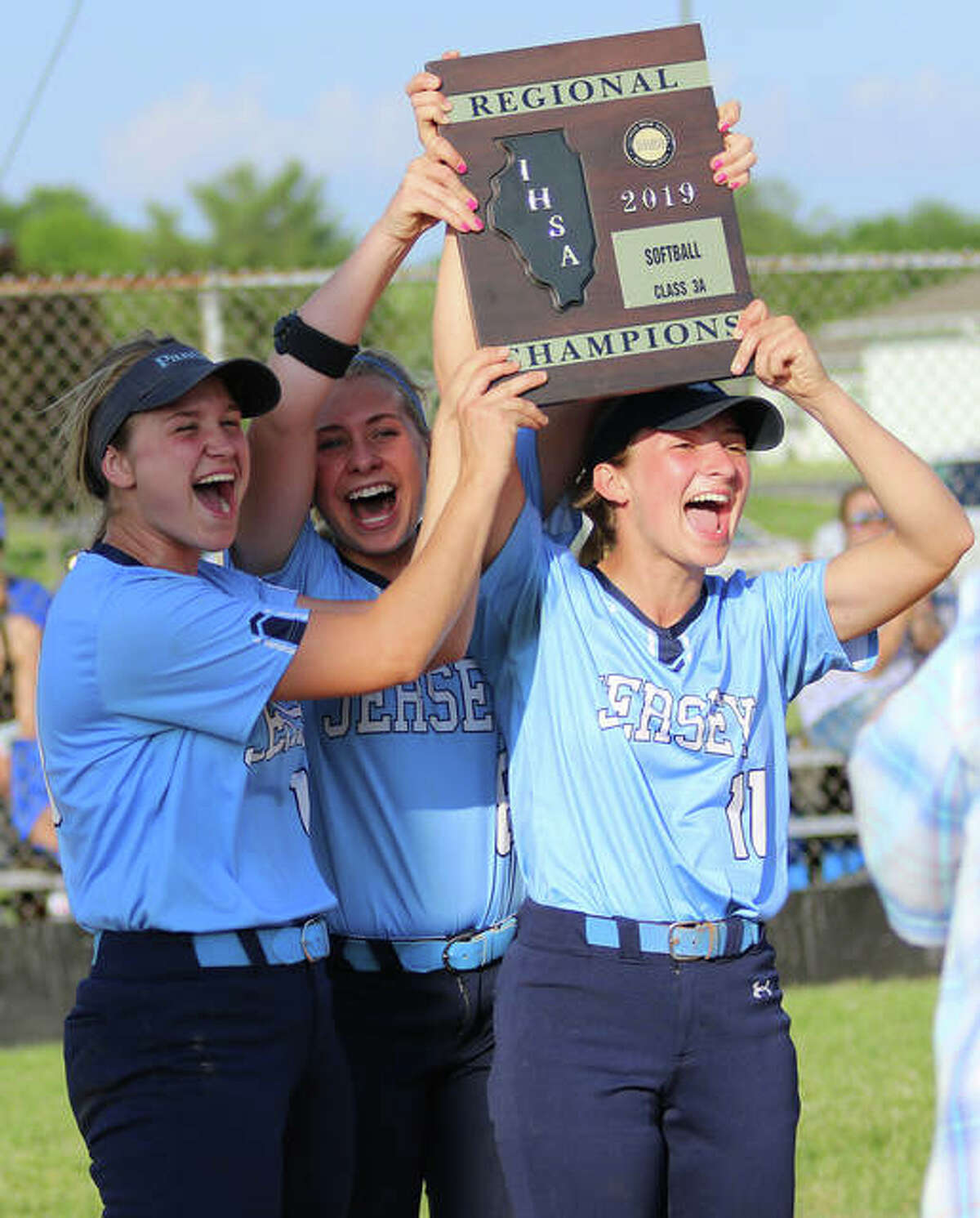 Jersey senior captains (from left) Chelsea Maag, Melissa Weishaupt and Brooke Tuttle deliver the Class 3A regional championship plaque to teammates after beating Columbia 8-1 in the title game at Jerseyville. It is Jersey’s first regional title.