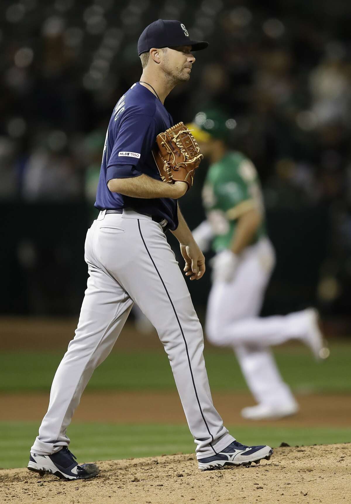 Seattle Mariners' Wade LeBlanc walks back on the mound after giving up a three-run home run to Oakland Athletics' Matt Olson, rear, during the fourth inning of a baseball game Friday, May 24, 2019, in Oakland, Calif. (AP Photo/Ben Margot)