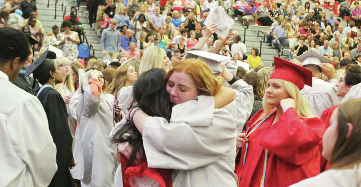 Two graduating Alton High School seniors hug after the Alton High School graduation ceremony Friday.