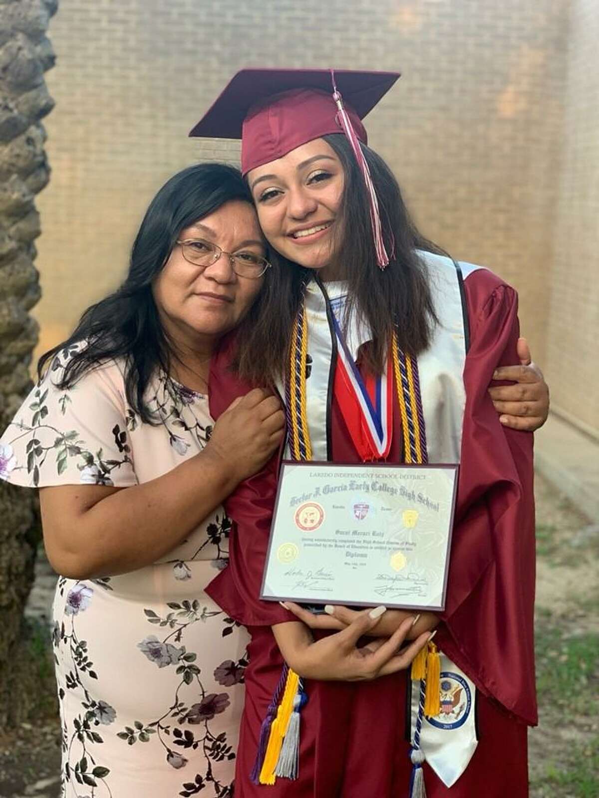 Saraí Ruiz is shown with her diploma alongside her mother after her graduation from Hector J. Garcia Early College High School.