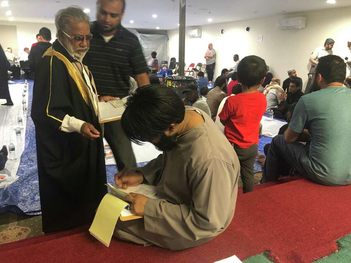 Abuhamza Hossain writes checks to Albany fire victims from Masjid As-Salam on Sunday, May 26, 2019 in Albany, N.Y. The Central Avenue mosque raised nearly $50,000 in a week for fire victims.