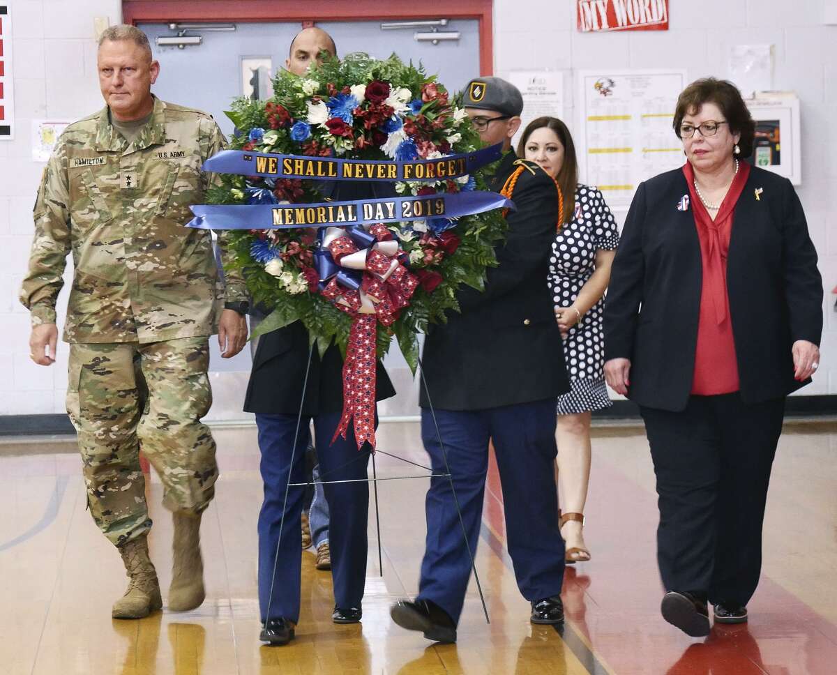 Major General Patrick Hamilton, left, LISD Superintendent Sylvia Rios, right, and others escort a memorial wreath.