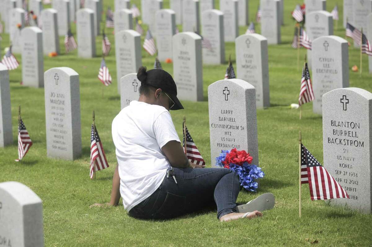 LaToya Stuart of Richmond, Texas, sits in front of her dad's gravesite at the Houston National Cemetery on Monday, May 27, 2019. Stuart's dad, Larry Cunningham Sr., served with the Navy during the Gulf War.