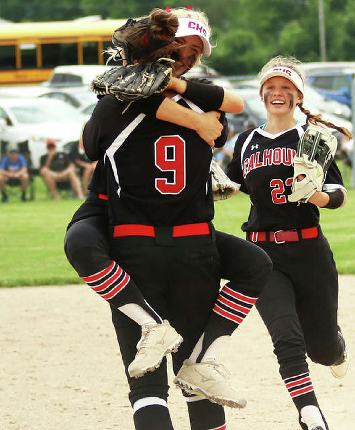 Calhoun pitcher Sydney Baalman gets a state-worthy hug from shortstop Sophie Lorton while second baseman Ashleigh Presley (right) comes to join the celebration after the Baalman’s 14th strikeout ended the game Saturday in Springfield.