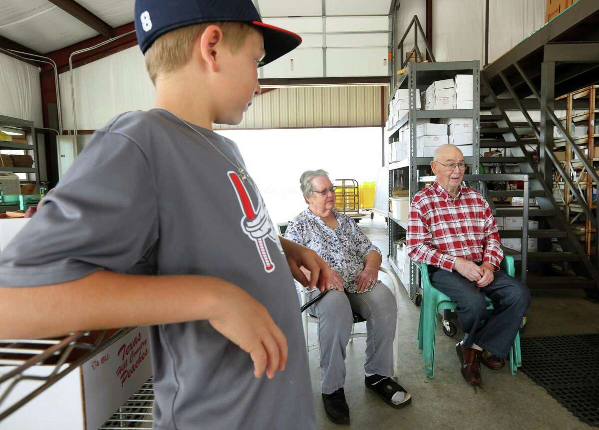 Quentin Eckhardt, left, listens Wednesday, May 22, 2019 to his grandparents, Carol, center, and Donald Eckhardt talk about the family's orchards at the family's peach stand on US 87 south of Fredericksburg. Virtually all Hill Country peach producers are reporting abundant crops of quality peaches.