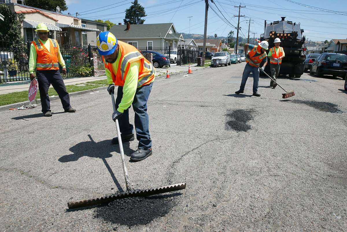 FILE - A maintenance crew from the Streets and Sidewalks department repairs potholes on 81st Avenue east of International Boulevard in Oakland, Calif. on Tuesday, May 28, 2019. Residents on the block said the potholes have been a problem for two years. Harold Street was recently repaved as part of the city's three-year pavement plan.