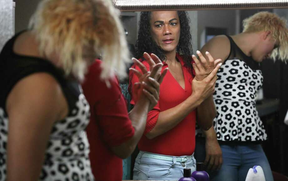 Mariena, center, checks herself in the bathroom mirror after putting on makeup as she and Escobar prepare to leave their hotel room. Photo: Bob Owen / ©2019 San Antonio Express-News