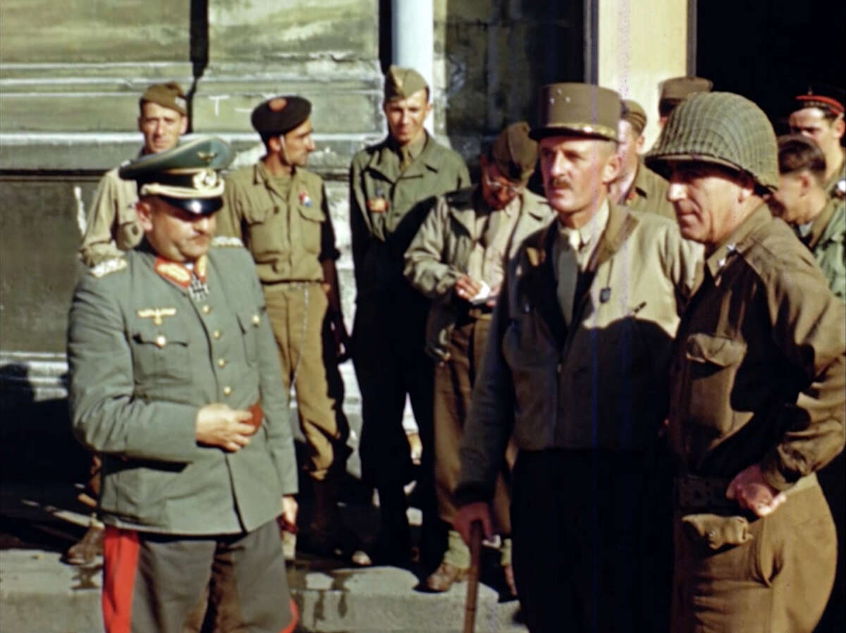 Gen. Phillippe Leclerc, foreground second right, stands with a captured German officer, left, after the liberation of Paris in 1944 during World War II. Seventy-five years later, surprising color images of the D-Day invasion and aftermath bring an immediacy to wartime memories. They were filmed by Hollywood director George Stevens and rediscovered years after his death. (War Footage From the George Stevens Collection at the Library of Congress via AP)