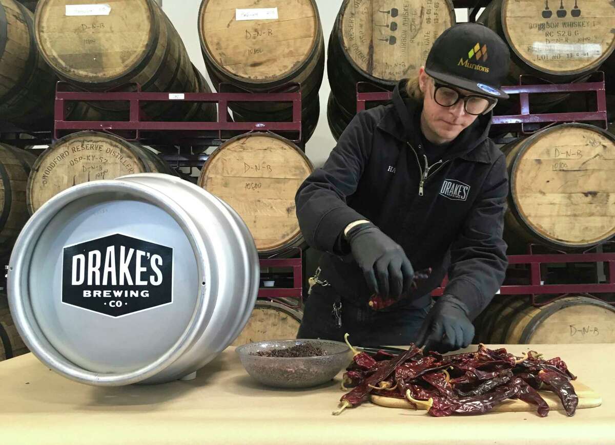 In this photo taken May 10, 2019, Hal McConnellogue, cellar manager at Drake's Brewing Company, works on putting chipotle peppers into a cask used to infuse beer with unique flavors in San Leandro, Calif. As craft breweries have boomed, competition for attention has intensified and that has a lot of brewers looking for ways to differentiate themselves by introducing strange new flavors. (AP Photo/Haven Daley)