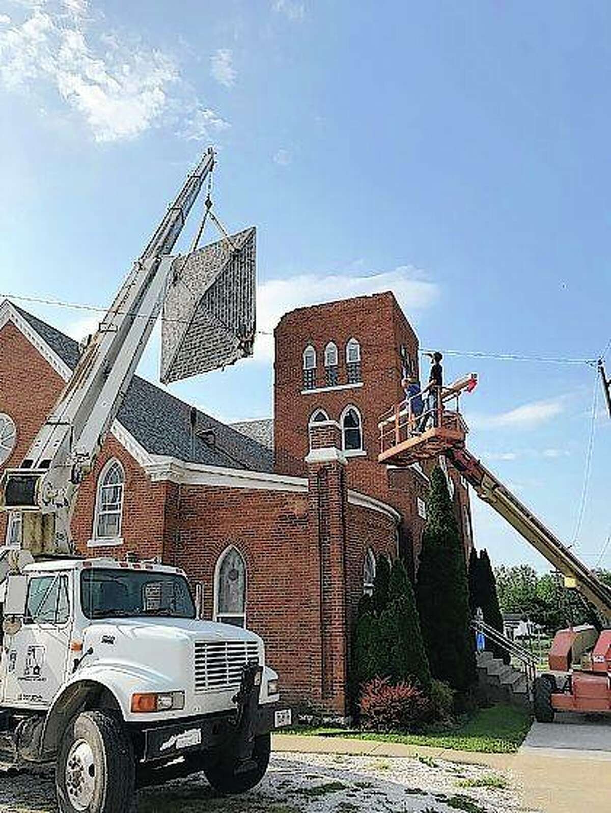 Crews work to clean up the damage at First Baptist Church in Roodhouse this week. The bell tower roof was lifted by strong winds and thrown onto the roof of the church Saturday evening.