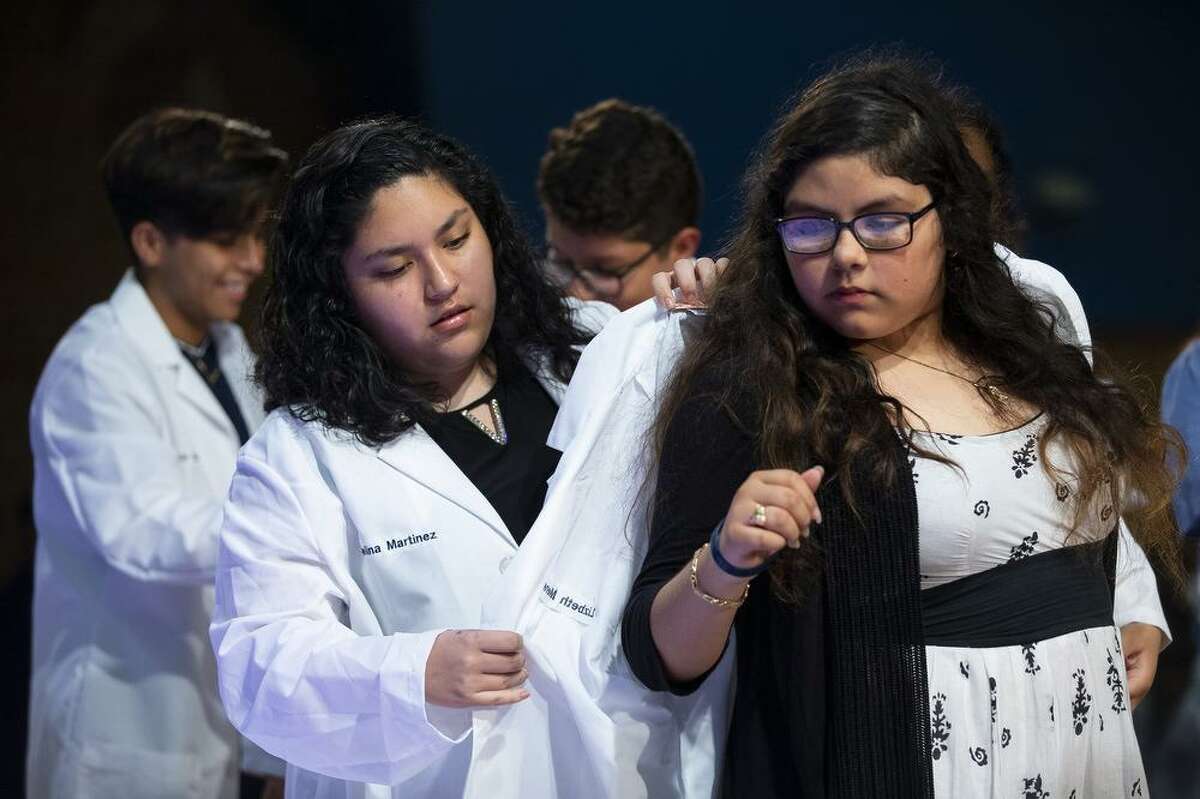 Angelina Martinez presents Lizbeth Menendez with her white coat during Jane Long Academy's annual White Coat Ceremony in the school's auditorium, Wednesday, May 22, 2019. The HISD school specializes in preparing students for careers in the medical field, specifically as pharmacy techs and medical coders. During the White Coat Ceremony, juniors and seniors present the freshman and sophomores their white coats.
