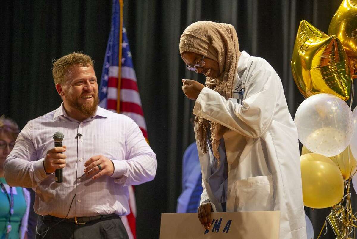 Scott Sullivan, of Citgo, presents student Fatuma Abdi with a scholarship check during Jane Long Academy's annual White Coat Ceremony in the school's auditorium, Wednesday, May 22, 2019. The HISD school specializes in preparing students for careers in the medical field, specifically as pharmacy techs and medical coders. During the White Coat Ceremony, juniors and seniors present the freshman and sophomores their white coats.