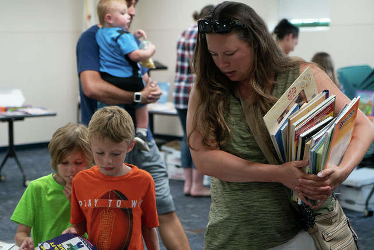 The Tri Township Book Sale has been canceled due to the weather. Pictured: Angela Caselli, of Edwardsville, shops for books with her two boys during an Edwardsville Library Friends’ Book Sale.