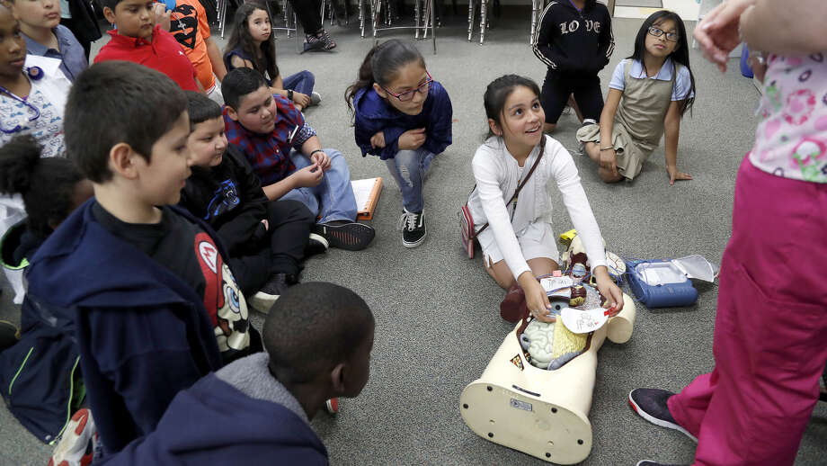 Angie Martinez, 9, looks up at Arial Hollow, a medical assistant, as she helped her demonstrate how to use a difibrilator during Career Day at MacArthur Elementary, a Gold Ribbon campus in Galena Park ISD, Thursday, May 23, 2019. Hollow is a former student at MacArthur Elementary and is part of the school's "homegrown" program. Photo: Karen Warren,  Houston Chronicle / Staff Photographer