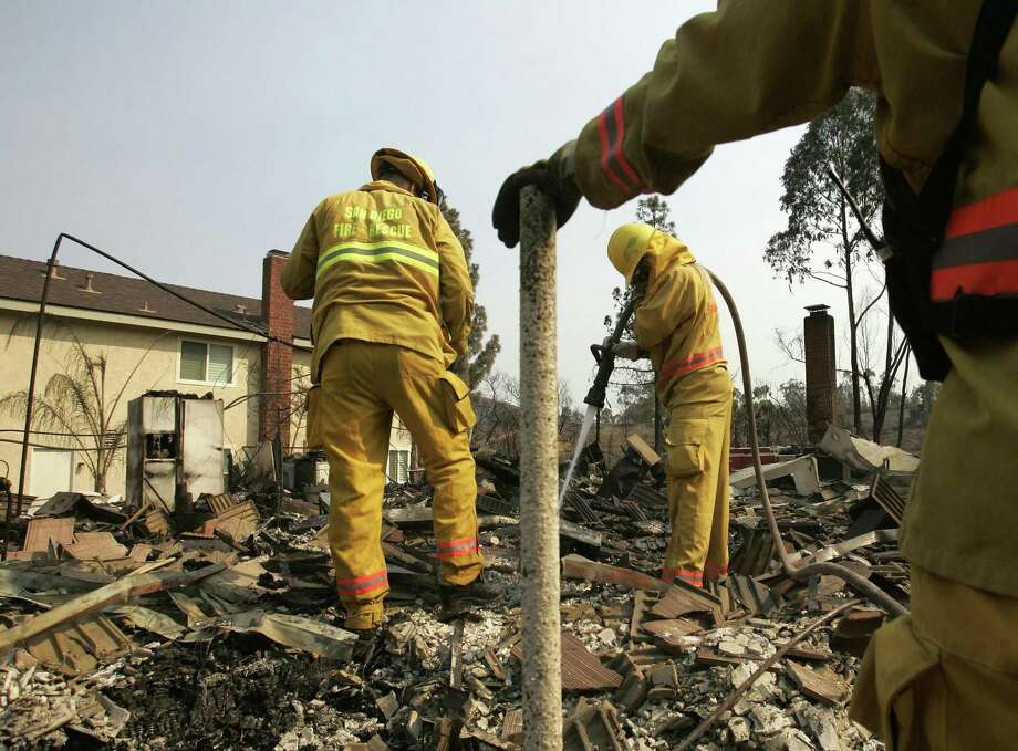 Firefighters douse a hot spot at a destroyed house in the Rancho Bernardo area of San Diego following the Witch Fire on Oct. 25, 2007. Photo: Chris Carlson / Associated Press / AP2007
