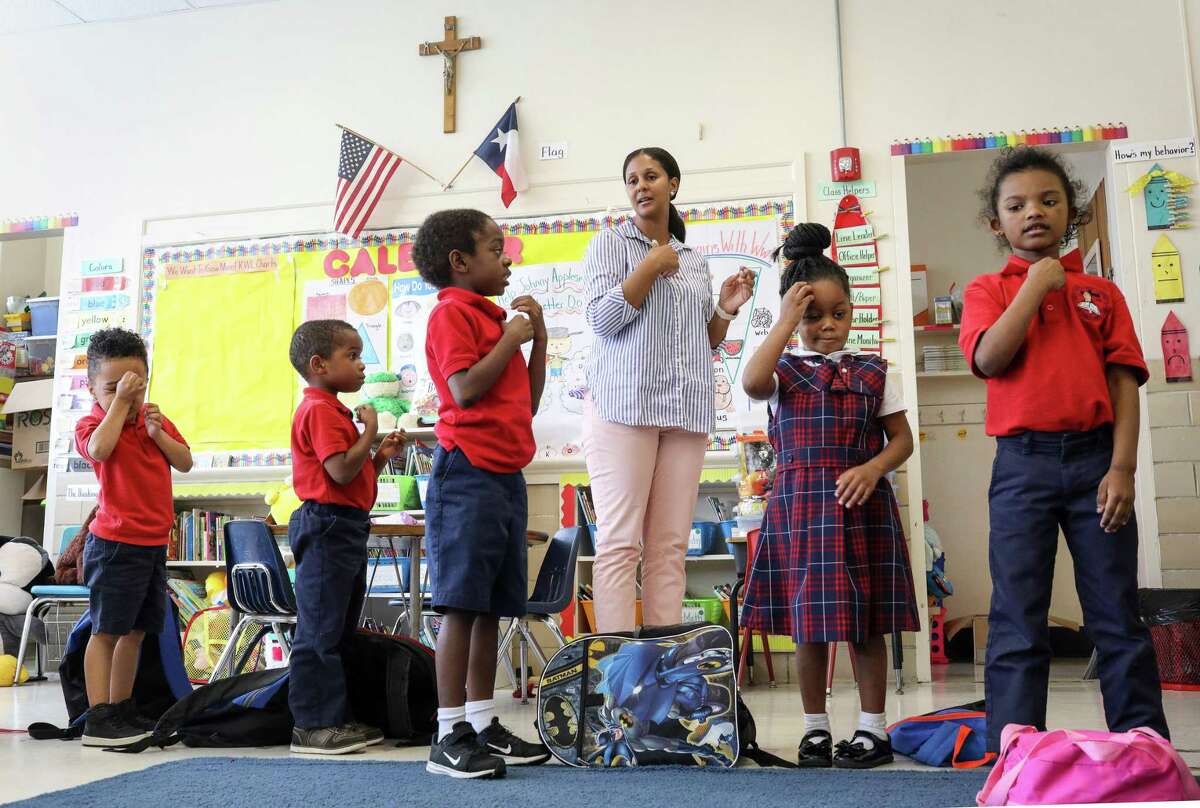 Julie Cook, pictured in May 2019, leads her students in making the sign of the cross after a prayer at the end of the school day at Saint Peter the Apostle Catholic School in Houston. The campus closed following that school year, and four other local private schools announced they will shutter this year amid the COVID-19 pandemic.