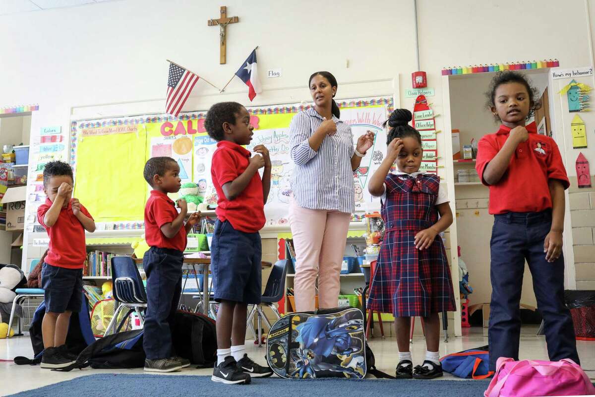 Julie Cook, pictured in May 2019, leads her students in making the sign of the cross after a prayer at the end of the school day at Saint Peter the Apostle Catholic School in Houston. The campus closed following that school year, and four other local private schools announced they will shutter this year amid the COVID-19 pandemic.
