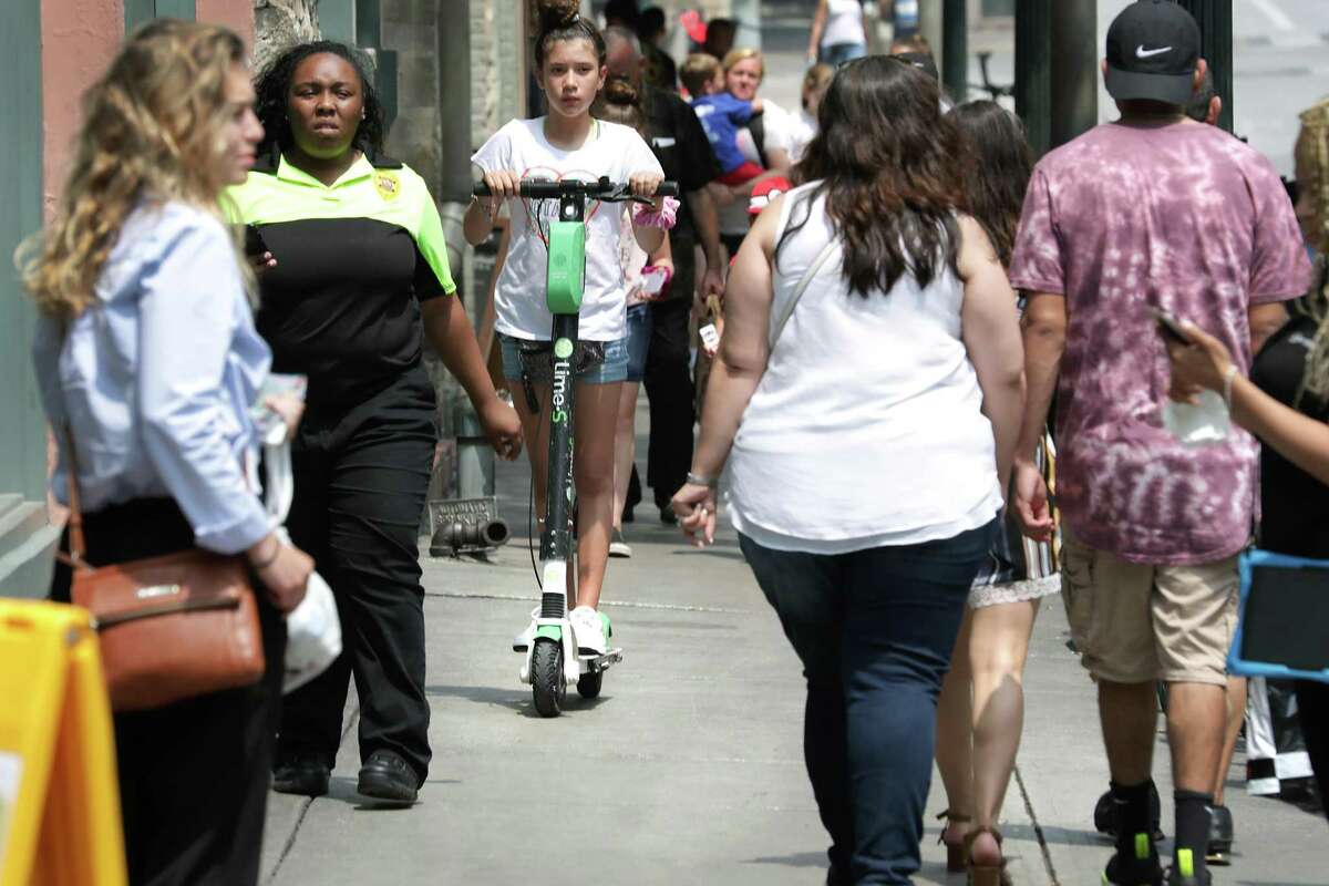 A young girl rides a scooter on a crowded side walk on Commerce Street on Thursday, May, 30, 2019. The City Council voted to ban riding scooters on sidewalks by June 30.
