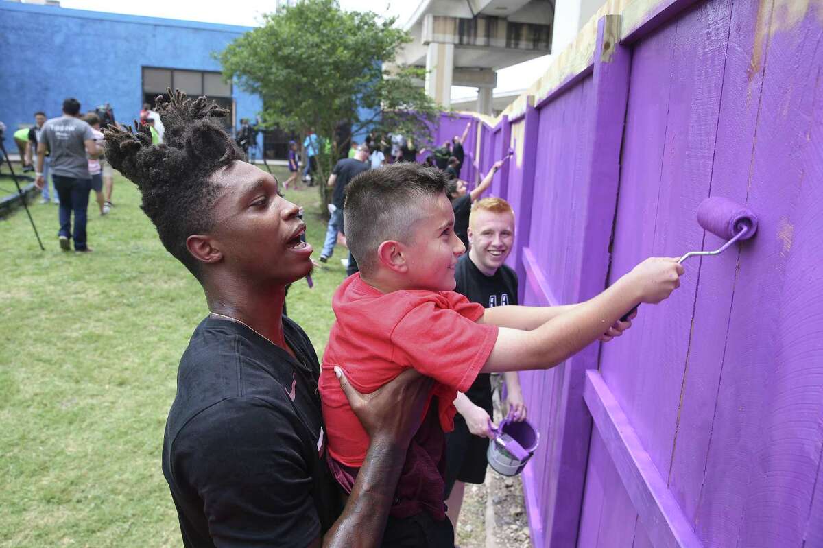 Spurs' Lonnie Walker, IV (left) gives nine-year-old Mario Barrera a lift to paint the upper sections of fencing as Spurs players and staff pay a visit to SA Youth to help them paint and refurbish the playscape and fence line on the nonprofit’s 1215 W. Poplar Street campus to help promote a healthy and active lifestyle on Thursday, May 30, 2019. Last year, Silver and Black Give Back donated a new basketball court for the more than 1,500 children served by SA Youth through Operation Renovation. Walker joined by teammates Drew Eubanks, Chimezie Metu and Ben Moore as they were all-hands-on-deck when joining kids and volunteers from SA Youth and Spurs Sports & Entertainment to put the finishing touches on the refurbished playground and help provide a safer space to learn, grow, and play. (Kin Man Hui/San Antonio Express-News)