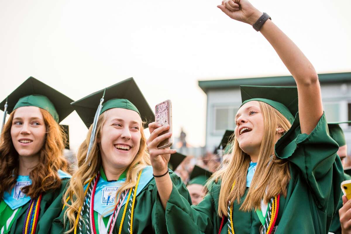 Graduate Taylor Bakos, right, cheers on a friend as Madison Wegner, left, laughs at the Freeland High School Commencement Ceremony on Thursday. (Danielle McGrew Tenbusch/for the Daily News)