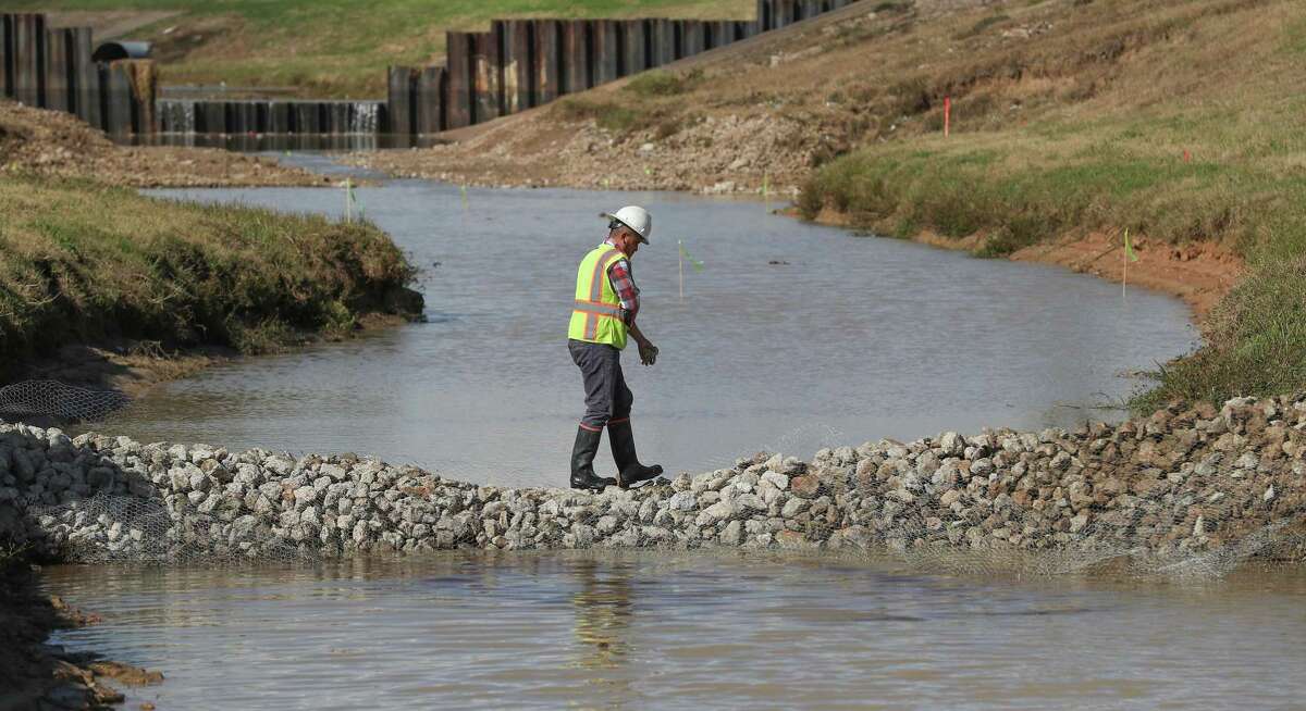 A worker crosses a temporary silt dam as the Harris County Flood Control District repairs damage caused by Hurricane Harvey near Fry Road and Bear Creek Friday, Nov. 30, 2018, in Katy.