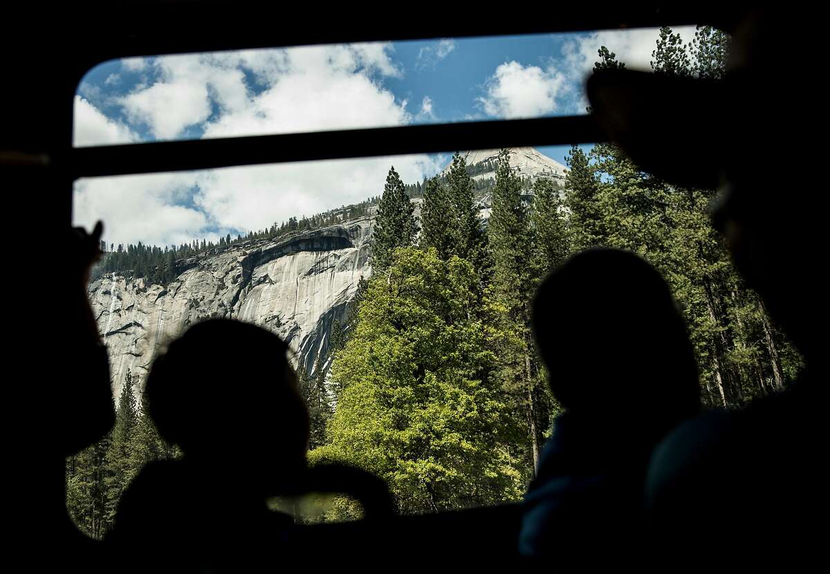 Hikers and tourists gaze at a view from the window of a crowded shuttle bus as it moves through Yosemite Valley inside Yosemite National Park in Yosemite, Calif. Tuesday, May 28, 2019.