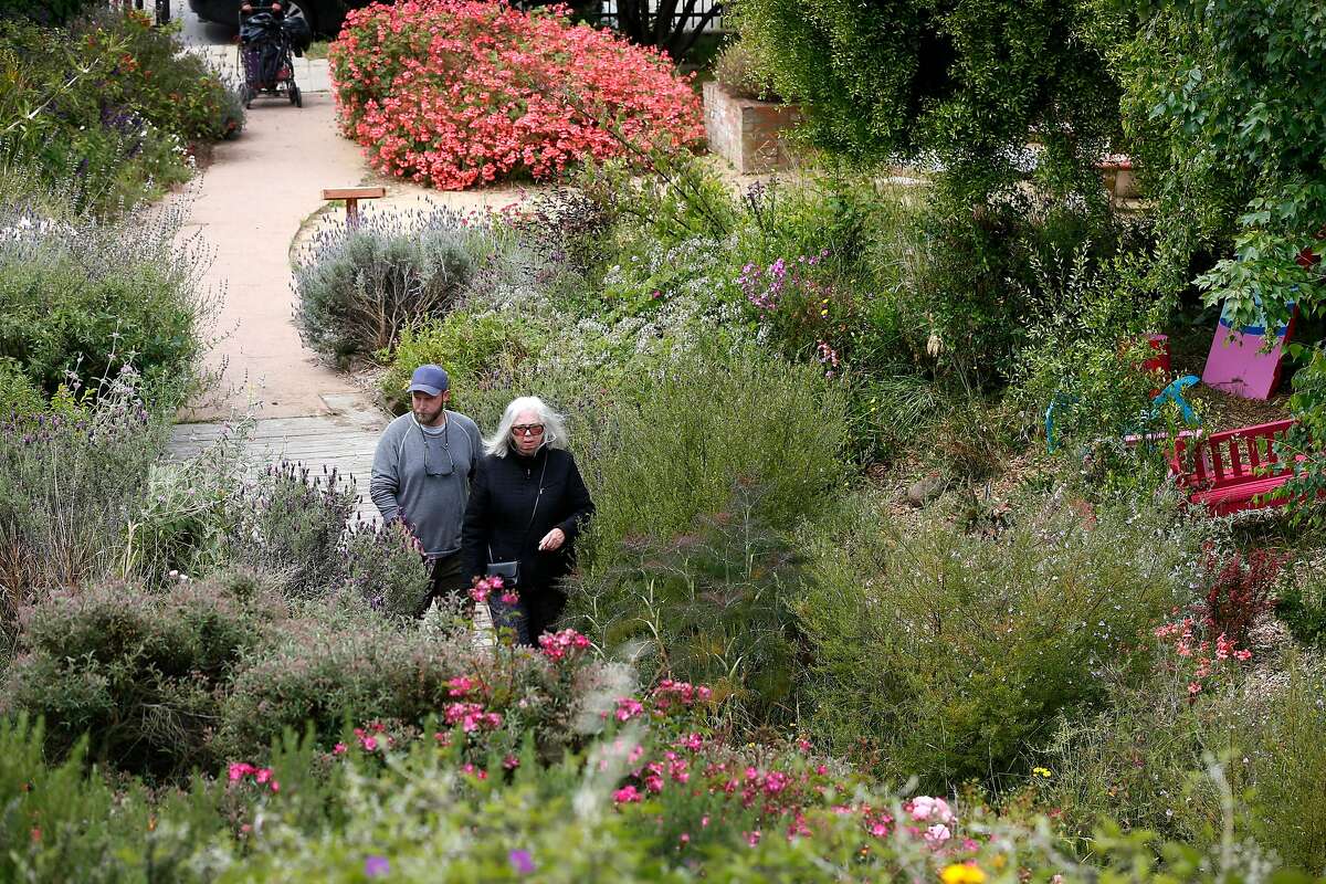 Fran Martin (right), co-founder of the Visitacion Valley Greenway, walks on the path with Brian Perrin, curator of a sculpture exhibit located in the herb garden section of the park in San Francisco, Calif. on Thursday, May 30, 2019.