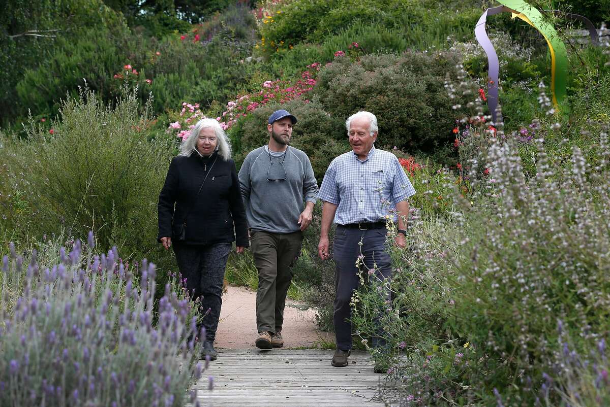 Fran Martin (left), co-founder of the Visitacion Valley Greenway, walks on the path with Brian Perrin (center), curator of a sculpture exhibit located in the herb garden section of the park, and Bob Siegel in San Francisco, Calif. on Thursday, May 30, 2019.