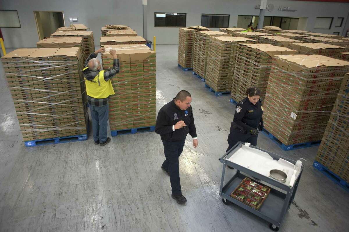 A U.S. Customs and Border Protection (CBP) officer, right, and a Servicio de Administracion Tributaria (SAT) officer, center, prepare to inspect strawberries at the CBP-SAT Pre-inspection Pilot Facility in Tijuana, Mexico. The conflict over trade adds to tensions in the U.S.-Mexico relationship.