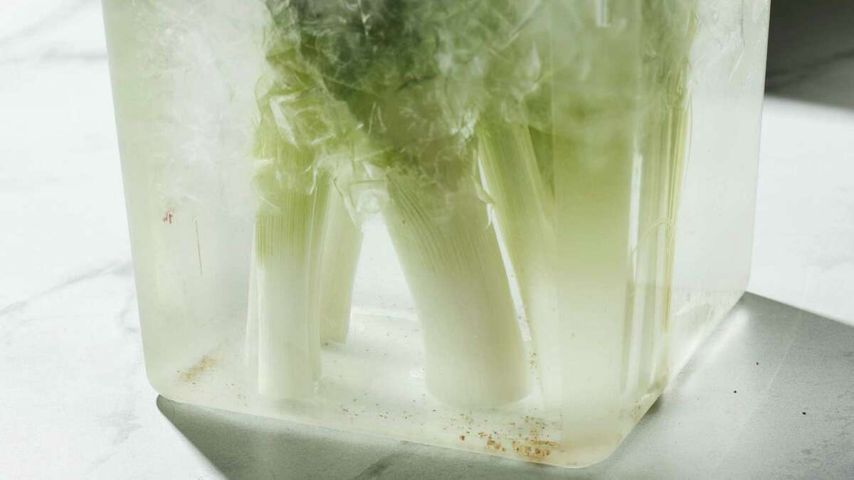 Leeks grow in layers that trap grit. To clean them, trim the top and bottom of the leeks and then cut them vertically in half. Stand them up in a container of ice water and let them soak for 15 minutes. You should see the grit drop to the bottom.