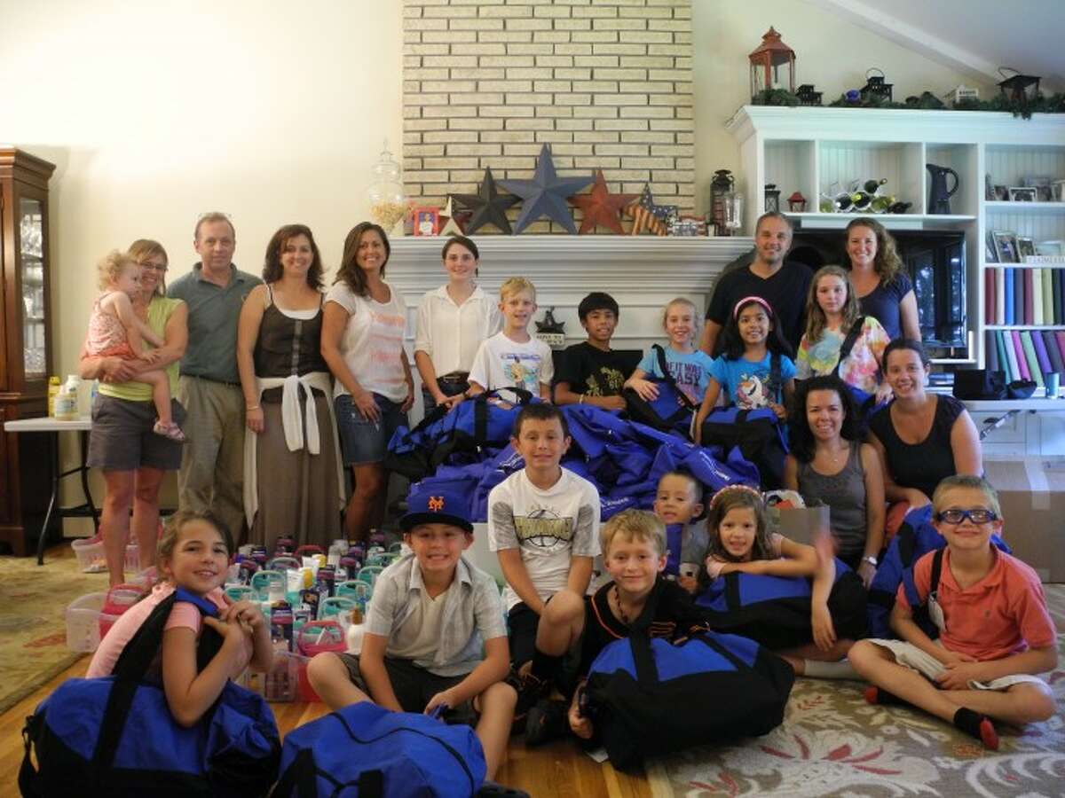 The Basbagill, Sommer, Bhagirathy, Fabrizio, and Wood families gather at the home of Jenn Record, president and founder of IMPACTrumbull, this summer. The non-profit group, which was formed in September 2012, collects, assembles and donates packages of goods to various charities in Fairfield and New Haven County. Thirty five IMPACTrumbull members and about 20 other community members donated to the group’s summer collections. — Steve Coulter