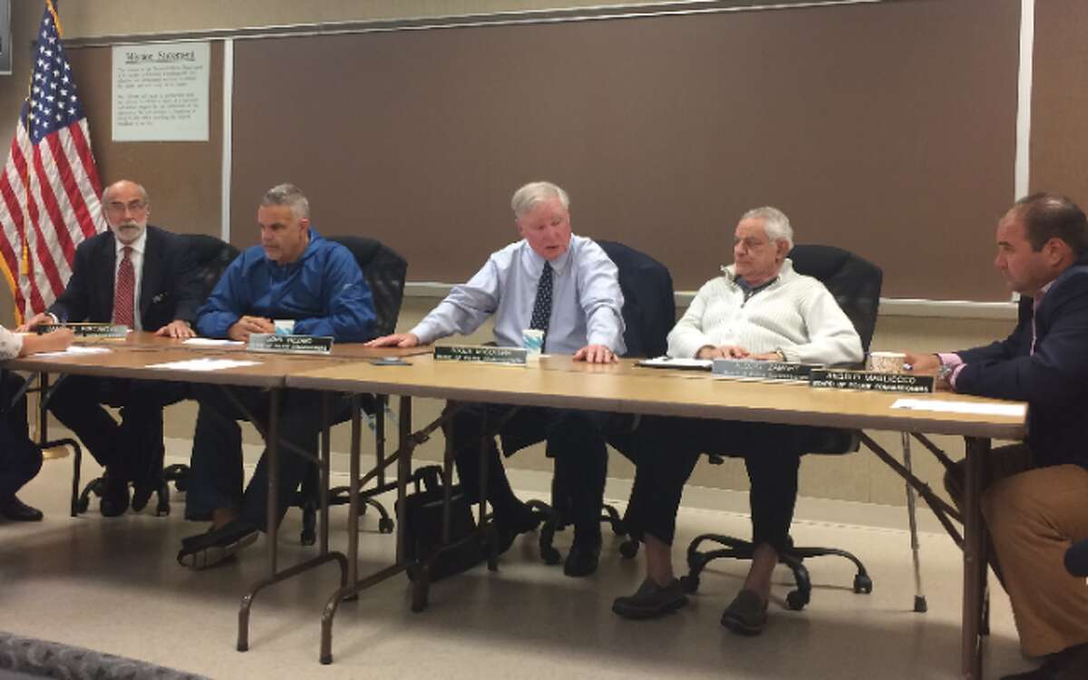 Police Commission Chairman Roger McGovern, center, reacts as Commissioner Daniel Portanova, left, reads a resolution referring McGovern to the Ethics Commission.