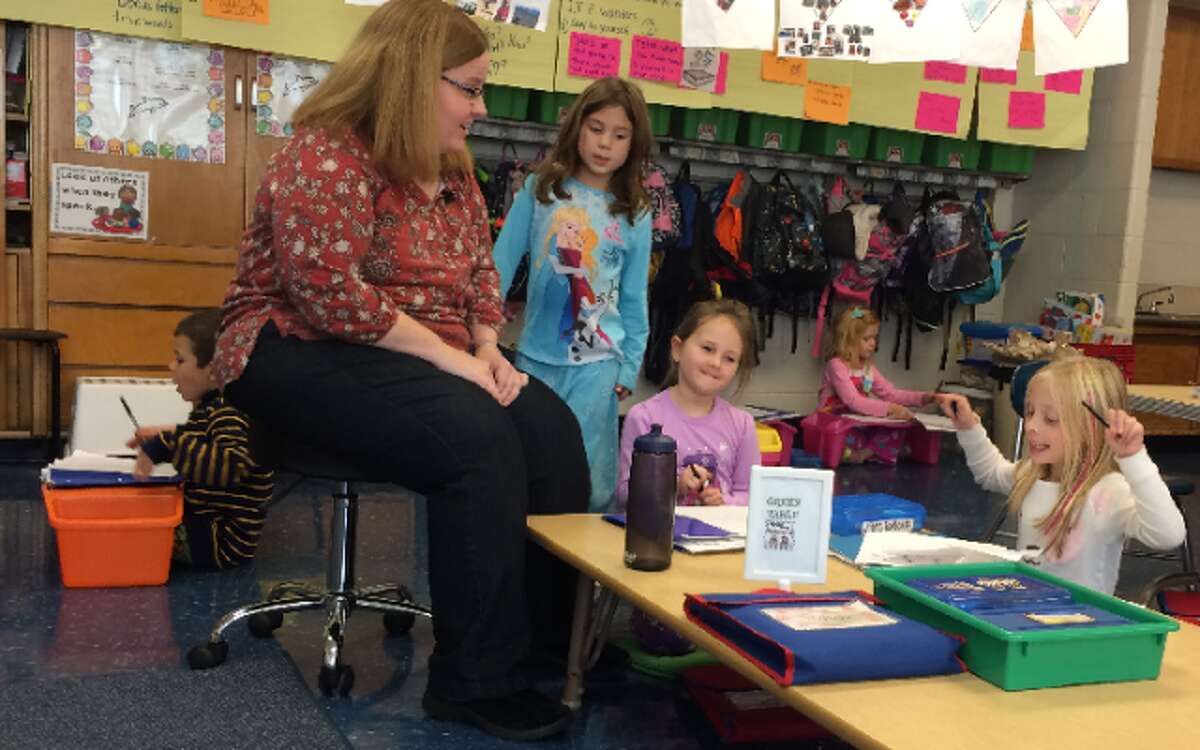 Elizabeth McGrath leads a writing exercise while students work at normal student chairs, on the floor at low tables, and at floor-based lap desks. — Donald Eng photo