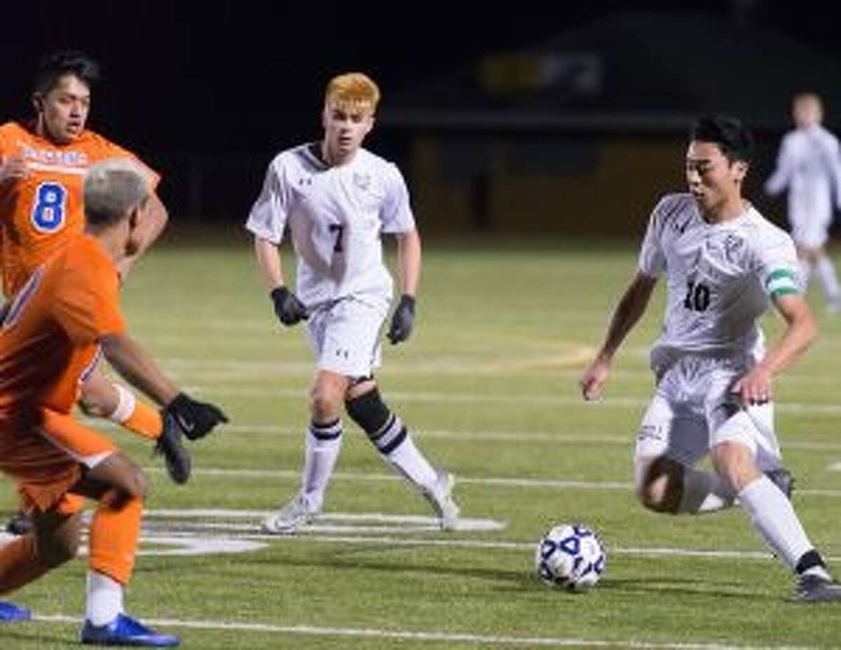 Trumbull's Thang Dao looks for an opening, as Danbury's Edwin Rosano (10) closes in.