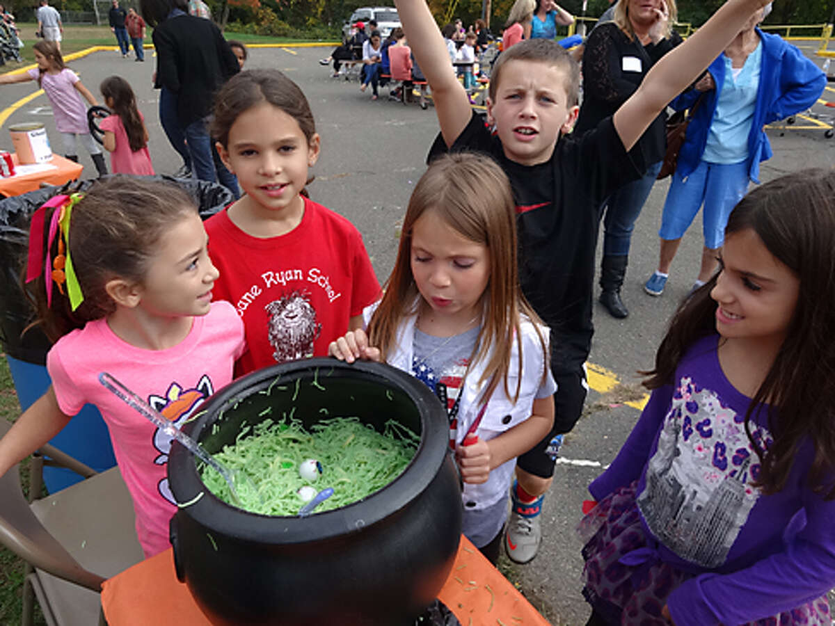 Madeleine Valiante, Elise Daly, an unidentified stew fan, and Kayla Ward (with a photobomb by George Kane) stare into the eyeball stew, one of the many games at the Jane Ryan Pumpkin Fair from a previous year.
