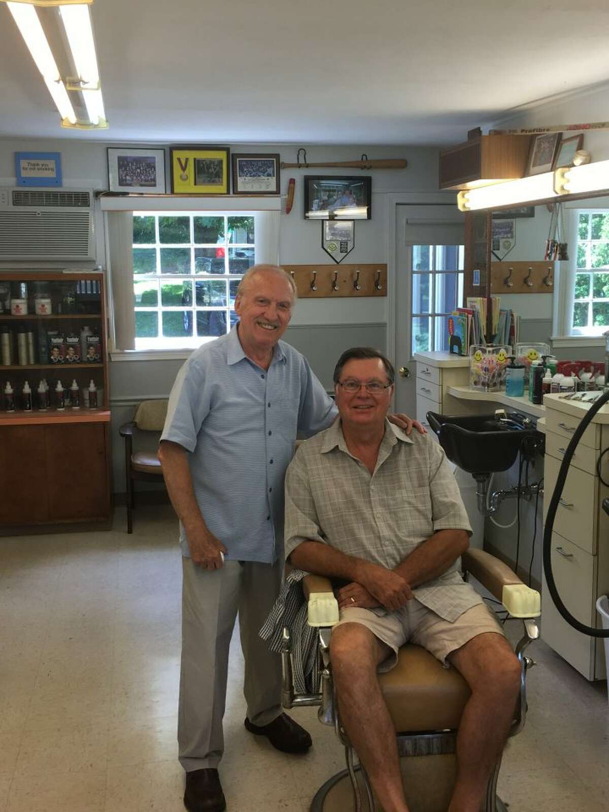 Nick Clericuzio, owner of Long Hill Hair Stylists, smiles with long-time customer Vincent Zujewski after completing a haircut on June 27. Zujewski, a member of Trumbull High School’s Class of 1968, has been going to Clericuzio’s barbershop since he was 16 years old. His most recent cut, which he will wear to his daughter’s wedding in California this month, marked the 50-year anniversary since his first trim at Long Hill Hairstylists in 1966. — Steve Coulter photo