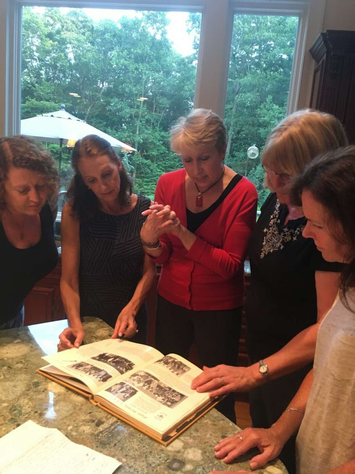 Members of the Class of 1976 gather around the yearbook, reminiscing on the different school clubs, trendy hangouts and music from the 1970s. — Steve Coulter photo