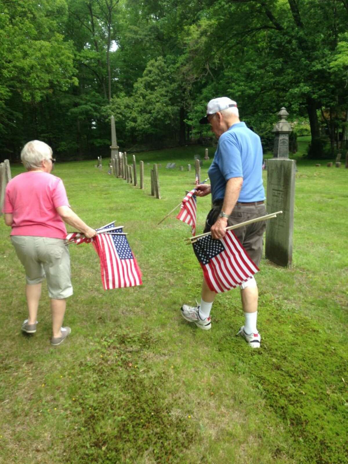 Trumbull residents Bill and Ruth Wakeley get ready to place flags at Riverside Cemetery.