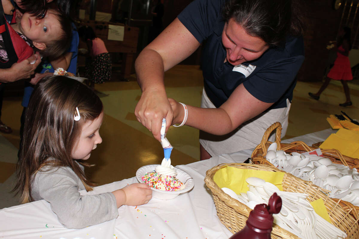 Annie Hughes, 3, accepts whip cream on her ice cream sundae from Trumbull High social studies teacher Katie Boland, adviser of the We the People team and ACE Foundation advisory board member. — Sue Berescik photo
