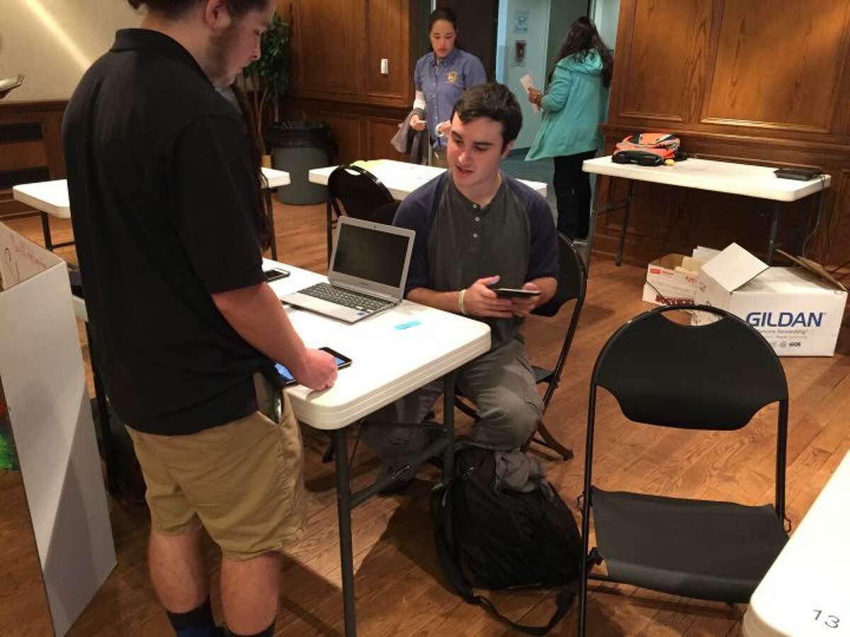 Trumbull High School senior Steven Baumann, seated, demonstrates his app TranslateU at the Mobile CSP App Expo in Hartford on May 24.
