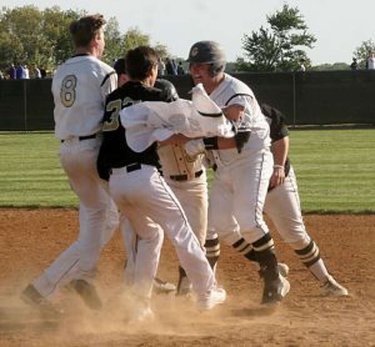 Trumbull High's Kris DiCocco draws a crowd after his RBI single plated the winning run. — Bill Bloxsom photos