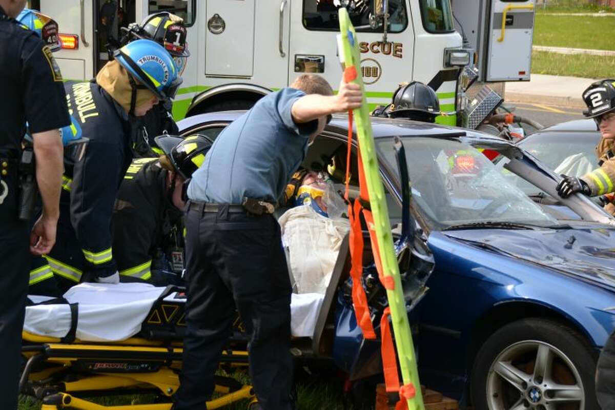 Trumbull police, fire, and EMS crews participate in a reenactment of a fatal car crash outside of Trumbull High School Friday, May 20. The mock car crash — the school's first in 13 years — was presented to the senior class with student actors playing the victims at the scene. Sirens could be heard by nearby residents as police cars and fire trucks descended on the scene. — Lisa Romanchick photo