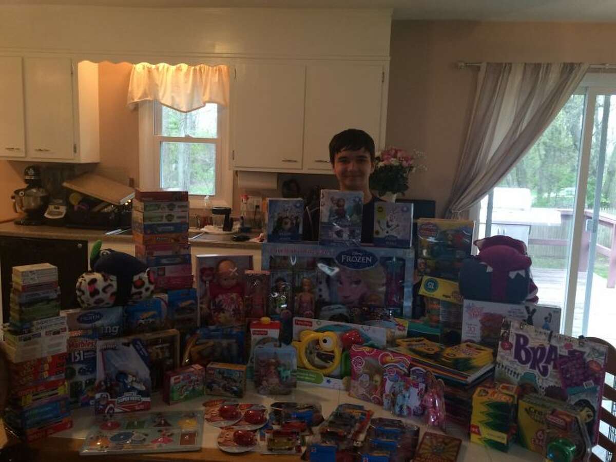 Madison Middle School student Ezekiel Cruz stands in his kitchen with all of the toys he collected.