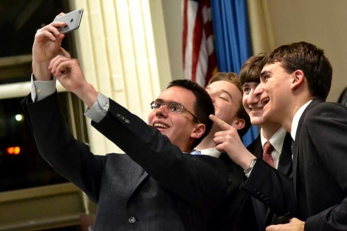 St. Joseph High School debate team member Ralph Rotondo holds up his iPhone to take a selfie with teammates Augustus LeRoux, Edward Szalan and Alexander Giannico after defeating the Trumbull High School at the Trumbull Library’s fifth annual One Book, One Town kick-off debate. — Lisa Romanchick photo