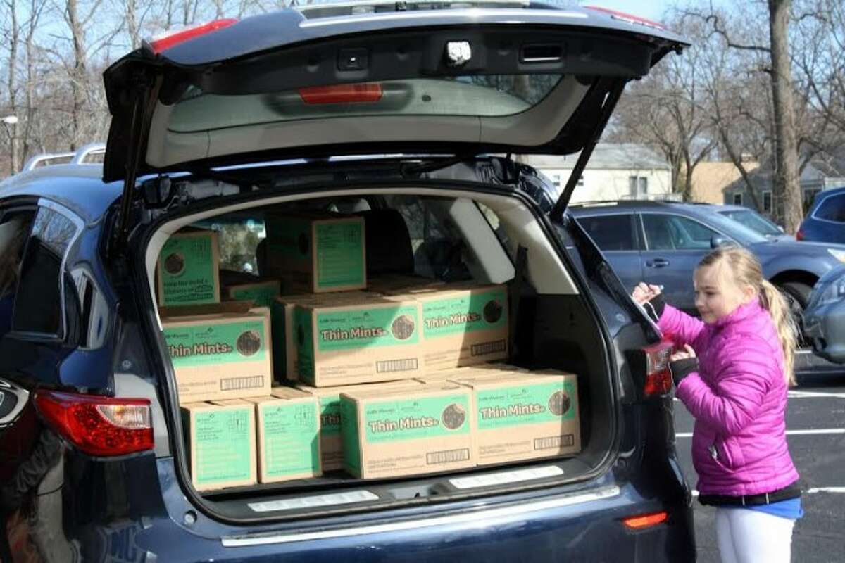 Girl Scout Brownie Caroline, from Trumbull Troop 36001, counts cases of cookies as they are loaded into her mom’s car during National Girl Scout Cookie Weekend and delivery in Connecticut.