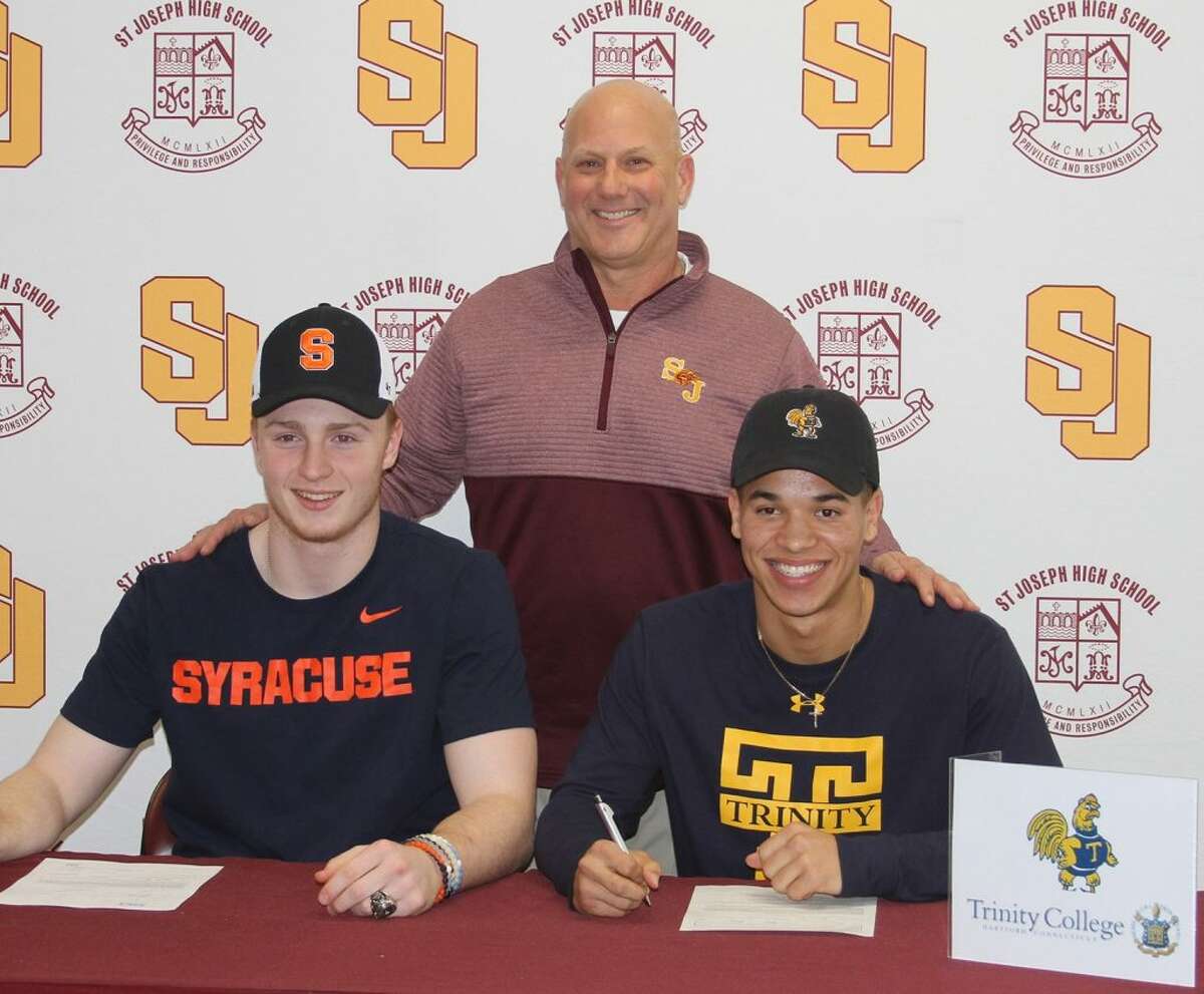 St. Joseph High football coach Joe Della Vecchia stands behind David Summers (Syracuse University) and Darren Warren (Trinity College) after they signed National Letters of Intent.Photo: St. Joseph High