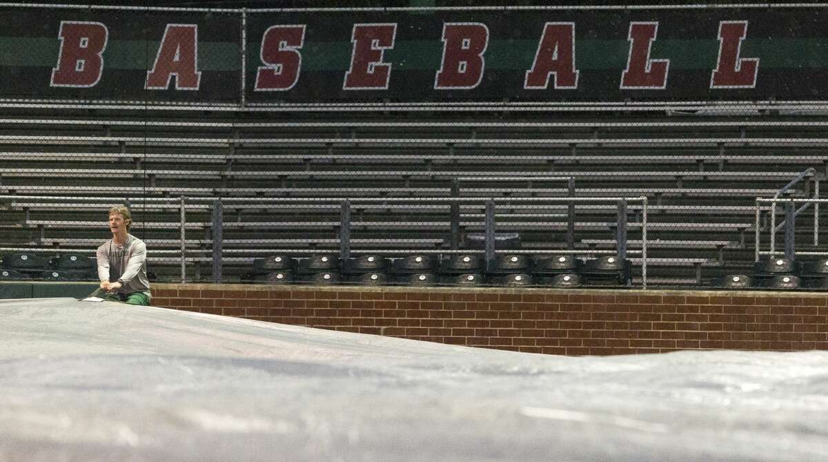 The Woodlands assistant coach John Hays helps tarp the infield of Scotland Yard after lightning interrupted Game 1 of Region II-6A bi-district high school baseball playoff series between The Woodlands and Aldine MacArthur, Thursday, May 2, 2019, in The Woodlands.