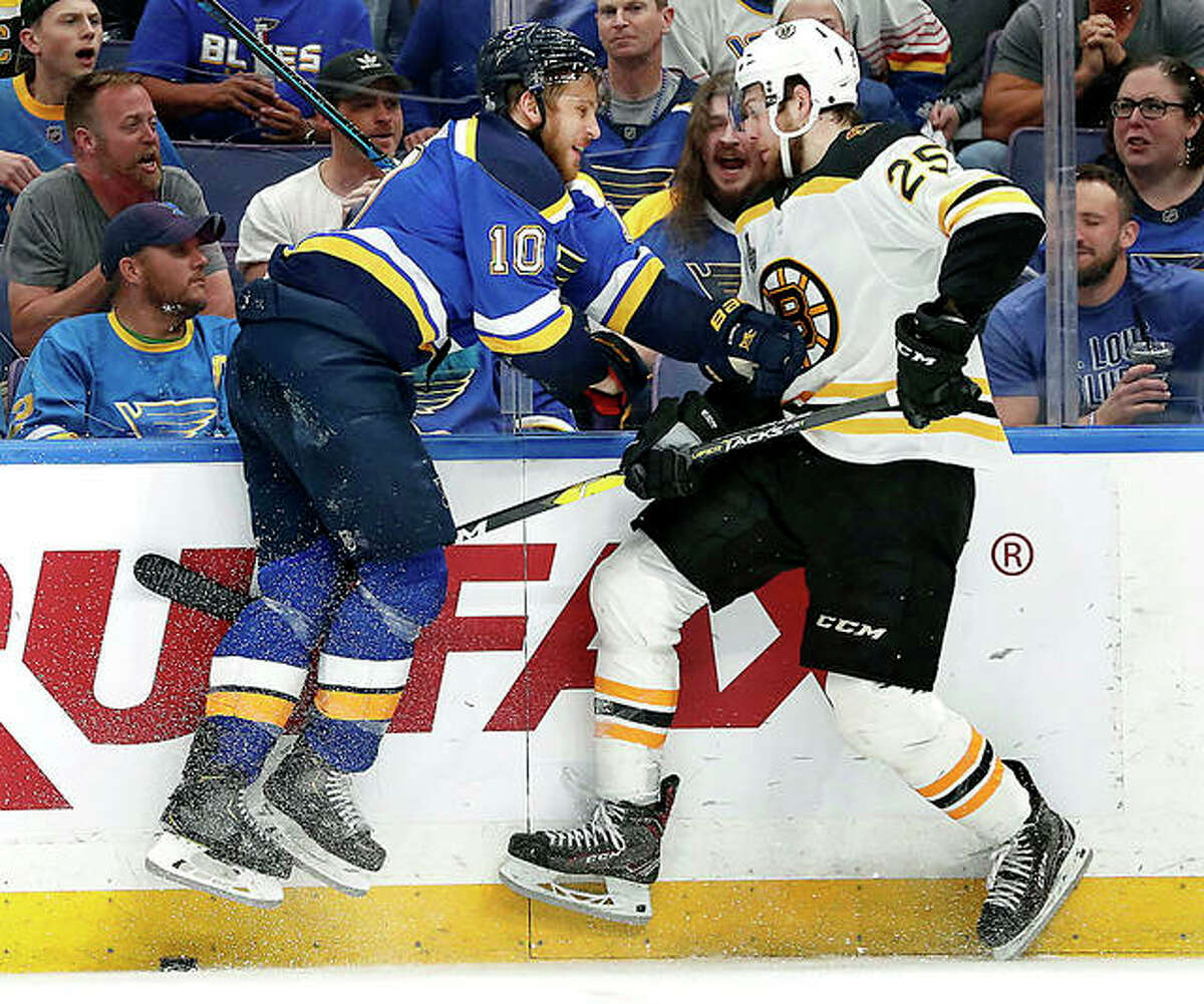Blues center Brayden Schenn (10) and Boston Bruins defenseman Brandon Carlo leave the ice as they battle for the puck in Monday night’s Game 4 of the Stanley Cup Final in St. Louis. The Blues won 4-2 to even the series 2-2.