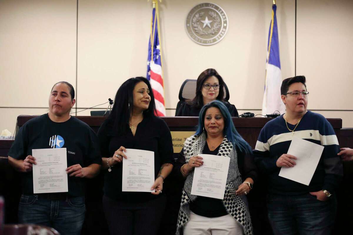 Holding back emotions, the San Antonio Four from left, Anna Vasquez, 43, Cassandra Rivera, 43, Elizabeth Ramirez, 44, and Kristie Mayhugh, 44 hold their orders granting the expunction of their criminal records signed by Bexar County 175th Criminal District Court Judge Catherine Torres-Stahl, in back, Monday, Dec. 3, 2018. They were wrongly convicted of sexually assaulting two girls in 1994. They were released from prison in 2013 and exonerated in November 23, 2016.