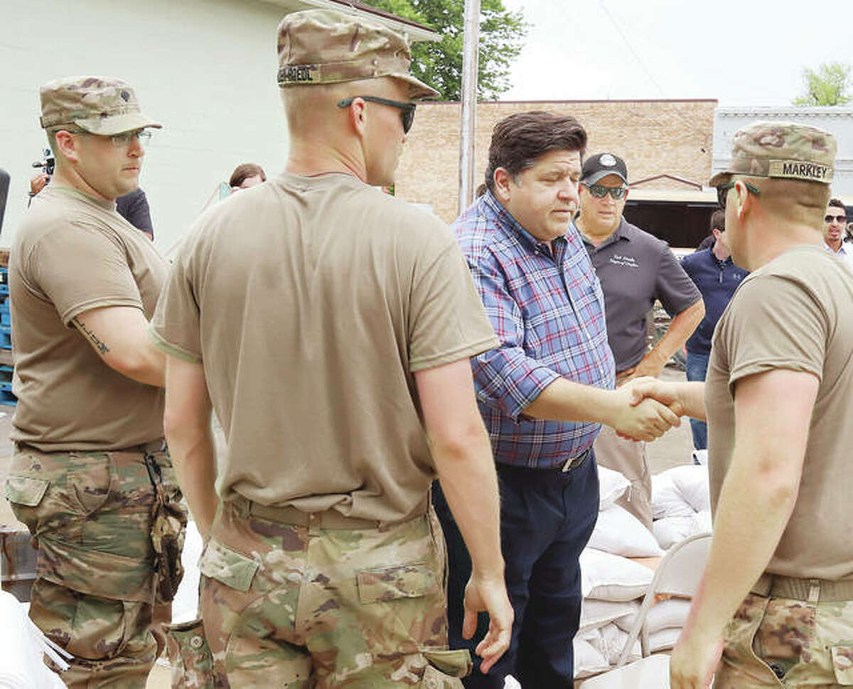 Illinois Gov. J.B. Pritzker, center, greets members of the Illinois National Guard Tuesday afternoon during a stop in Grafton to get a first hand look at flooding in the small towm. The guardsmen had been helping to fill sandbags.